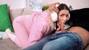 Brunette in a pink puffer jacket giving a couch blowjob while looking at the camera - HornySimp